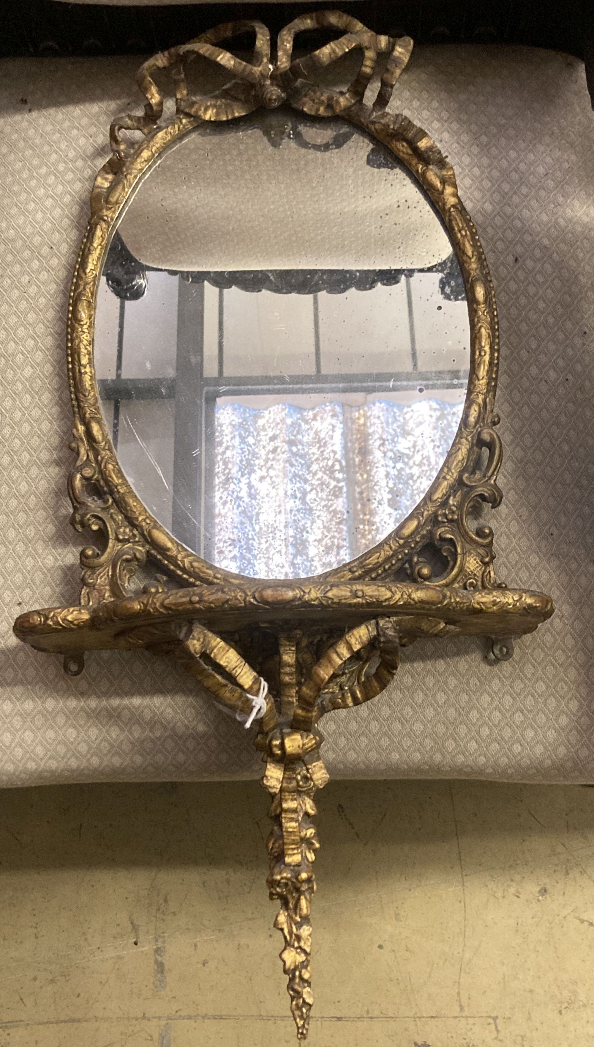 A Victorian oval giltwood and gesso mirrored wall bracket, width 38cm, height 78cm
